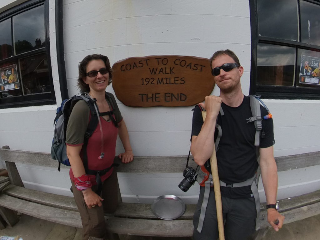 Manu & Markus vor der Plakette, die das Ende des  C2C in Robin Hood's Bay markiert