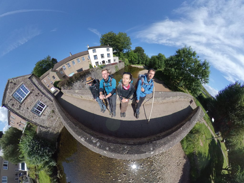 Wir vier genießen die Sonne auf einer kleinen Steinbrücke über einem Fluss