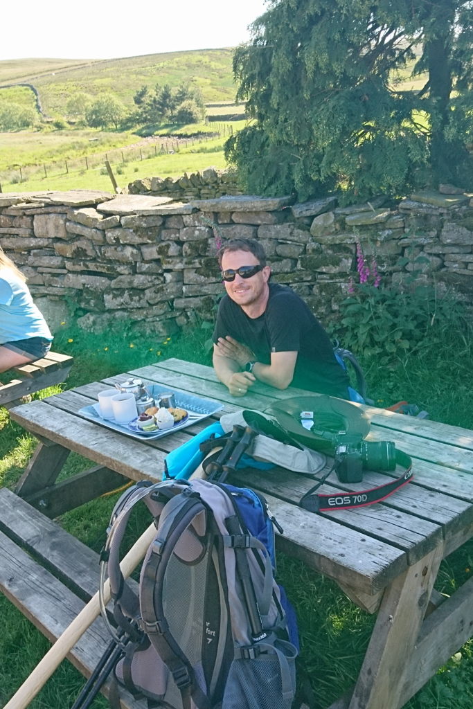 Markus lächelnd am Tisch mit zwei Cream Teas vor sich