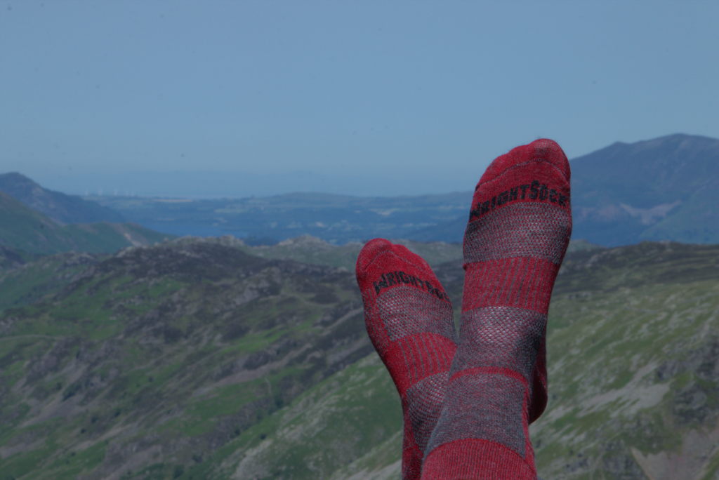 Manus Füße in roten Wandersocken mit Hügeln im Hintergrund