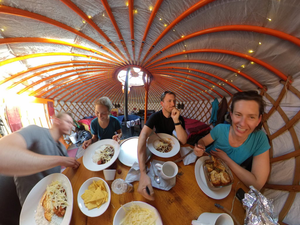 Wir vier sitzen um einen Tisch in der Jurte mit vier Tellern mit Essen vor uns.