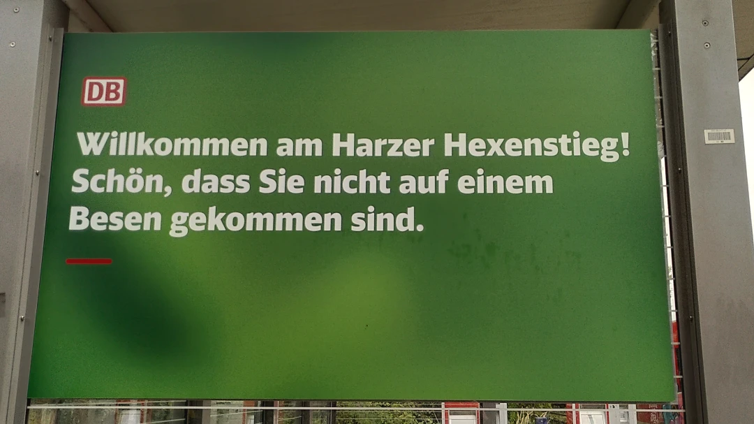Ein Plakat von der Deutschen Bahn mit der Aufschrift "Willkommen am Harzer Hexenstieg! Schön, dass Sie nicht auf einem Besen gekommen sind."