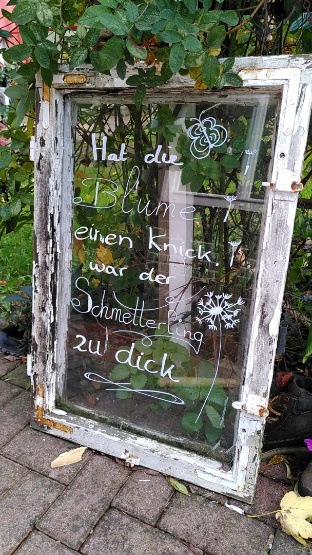 Eine Glasscheibe mit der Aufschrift "Hat die Blume einen Knick war der Schmetterling zu dick."