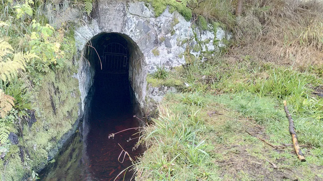A water ditch emerges from a small tunnel that led it through the mountain