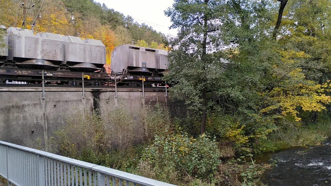 Einige staubige Eisenbahnwaggons fahren über eine Brücke