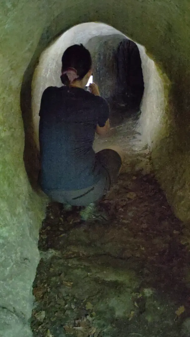 Manu in der Hocke fotografiert entlang eines engen Höhlengangs