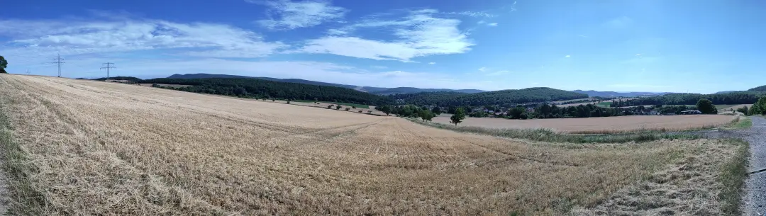 Panorama zurück in Richtung Alfeld über die rollenden Hügel. Im Vordergrund ein abgeerntetes Stoppelfeld