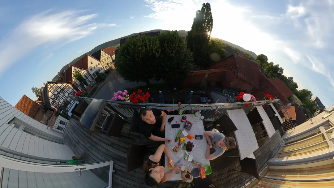 Blick auf Markus, Manu und Lütti direkt von oben um den Abendessenstisch. Der Tisch steht auf einem Balkon mit Blick über alte Fachwerkhäuser in Salzhemmendorf.