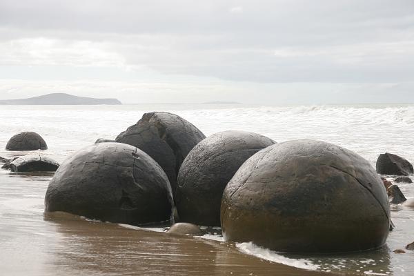 Eine Ansammlung großer Steinkugeln am Strand, vom Meer umspült