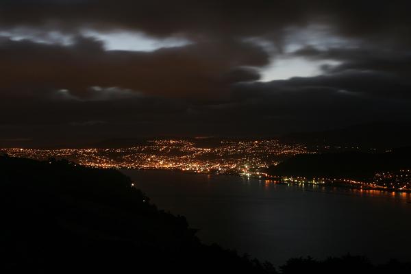 Blick über die (dunkle) Bucht auf das hell erleuchtete Dunedin