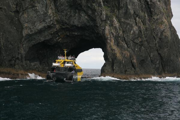 Ein Felstunnel im Meer mit einem Ausflugsboot davor