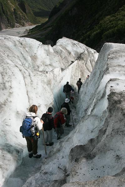 Mehrere Leute auf einer nach unten führenden Treppe, die ins Gletschereis eingeschnitten ist