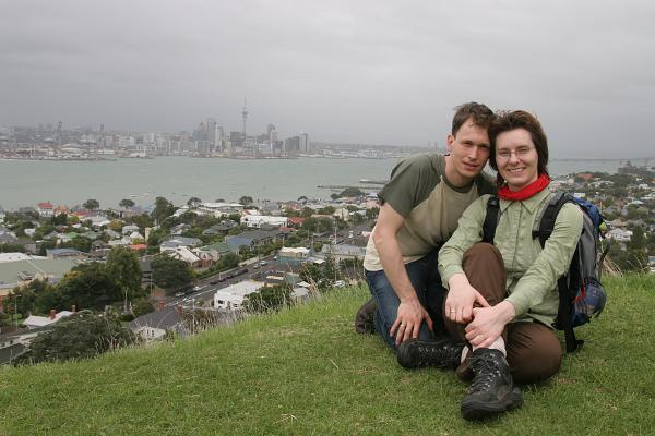 Manu & Markus vom Wind zerzaust. Im Hintergrund sieht man die Skyline Aucklands auf der anderen Seite der Bucht