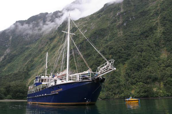 Ein Schiff vor den steil aufragenden Wänden des Fjords