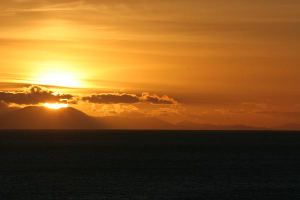 Sonnenuntergang über dem Meer. Am Horizont erkennt man Berge, die zur Südinsel gehören