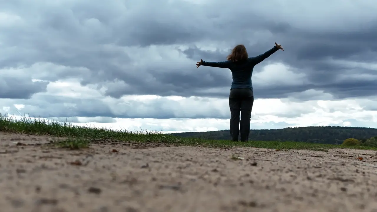 Manu from ground level against the sky with arms stretched out